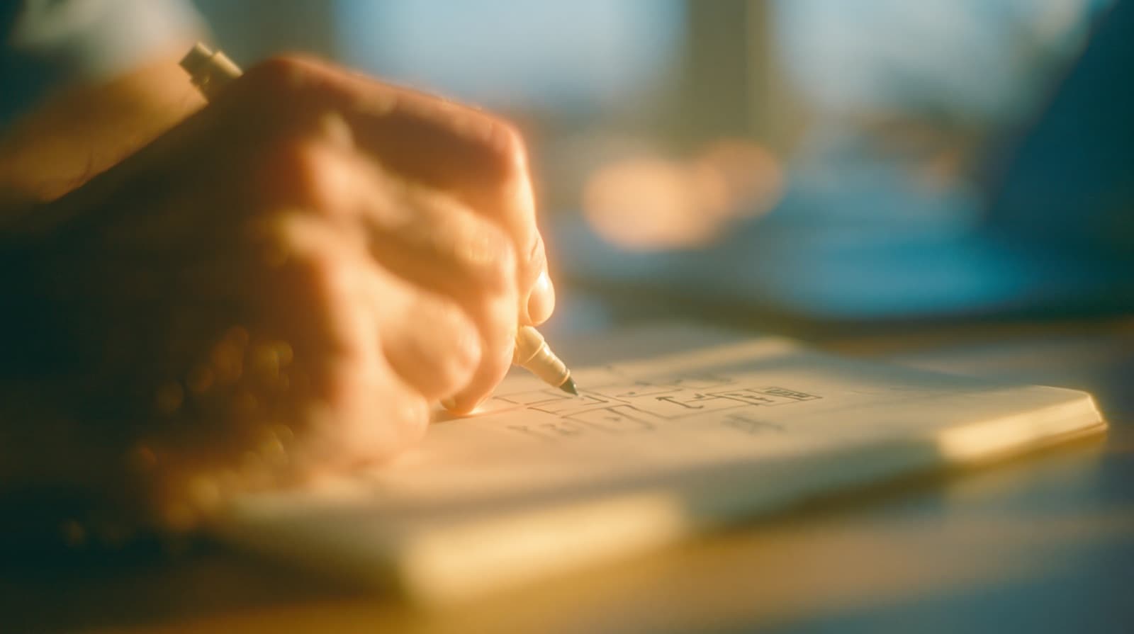 A hand sketching a simple workflow diagram in a notebook